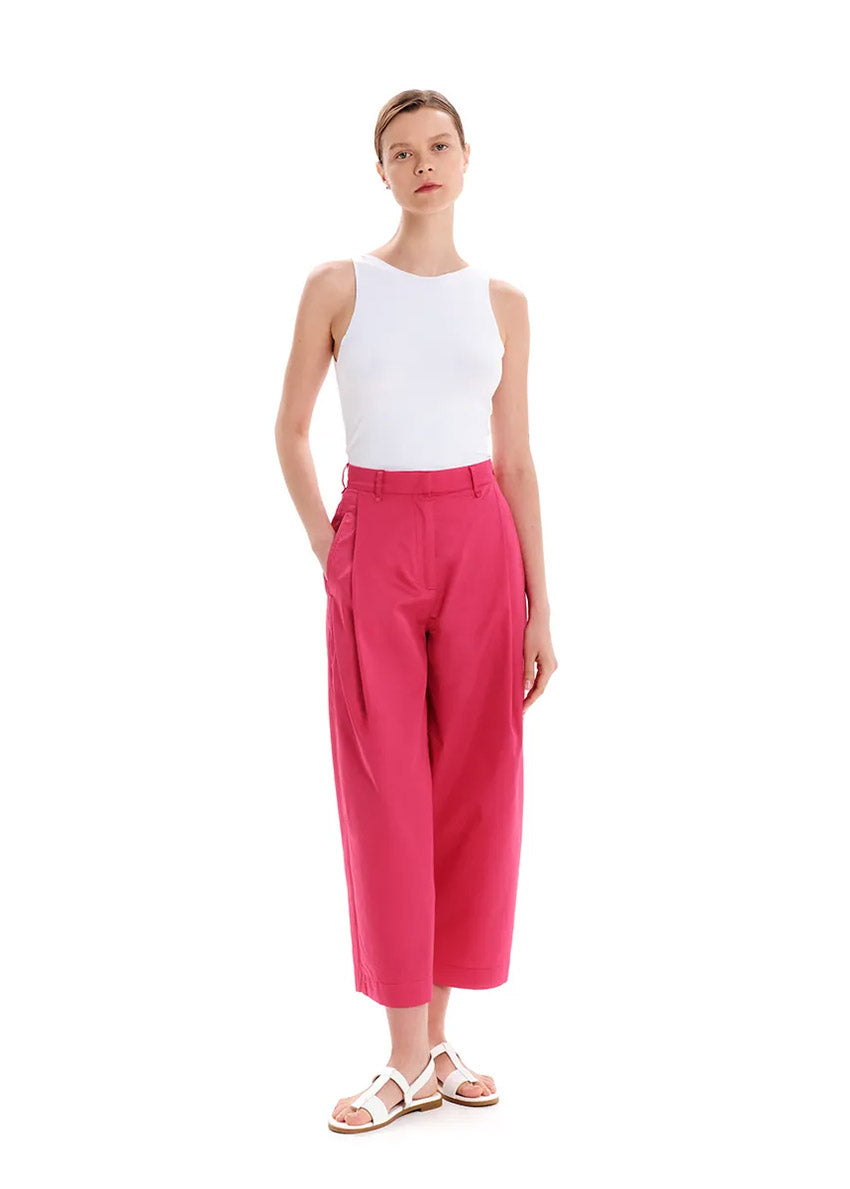 Person wearing a white tank top with pink trousers on a white background 