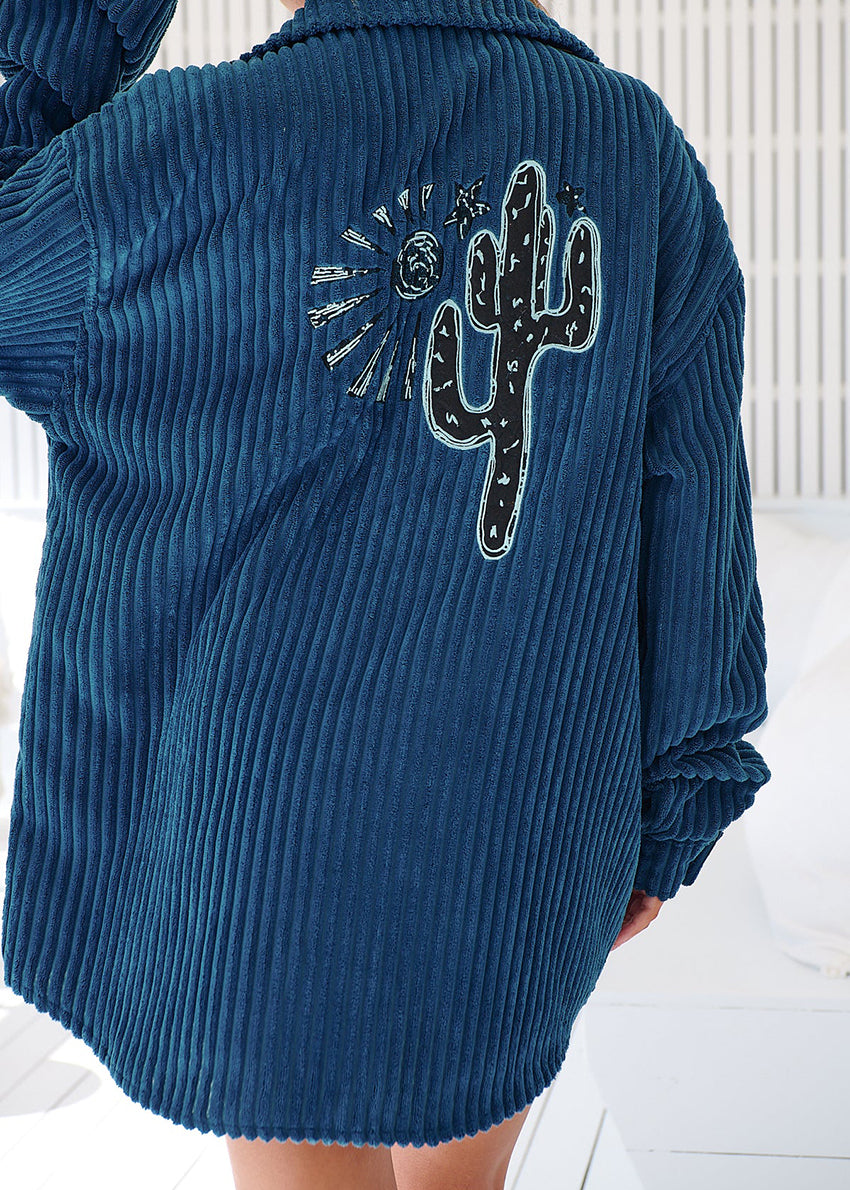 A woman wearing a navy blue corduroy jacket with long sleeves and a button-up front, paired with denim shorts.