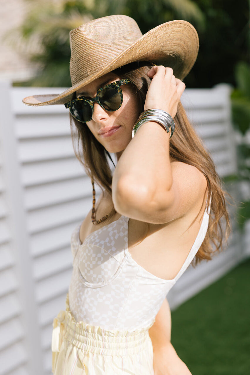 Woman wearing a wide-brimmed hat and sunglasses outdoors