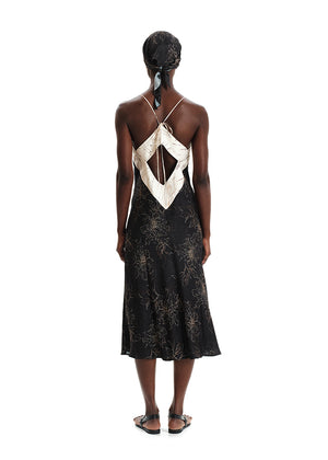 A model wearing a midi-length sleeveless dress with a floral print, a V-neckline, and tie details on the back.