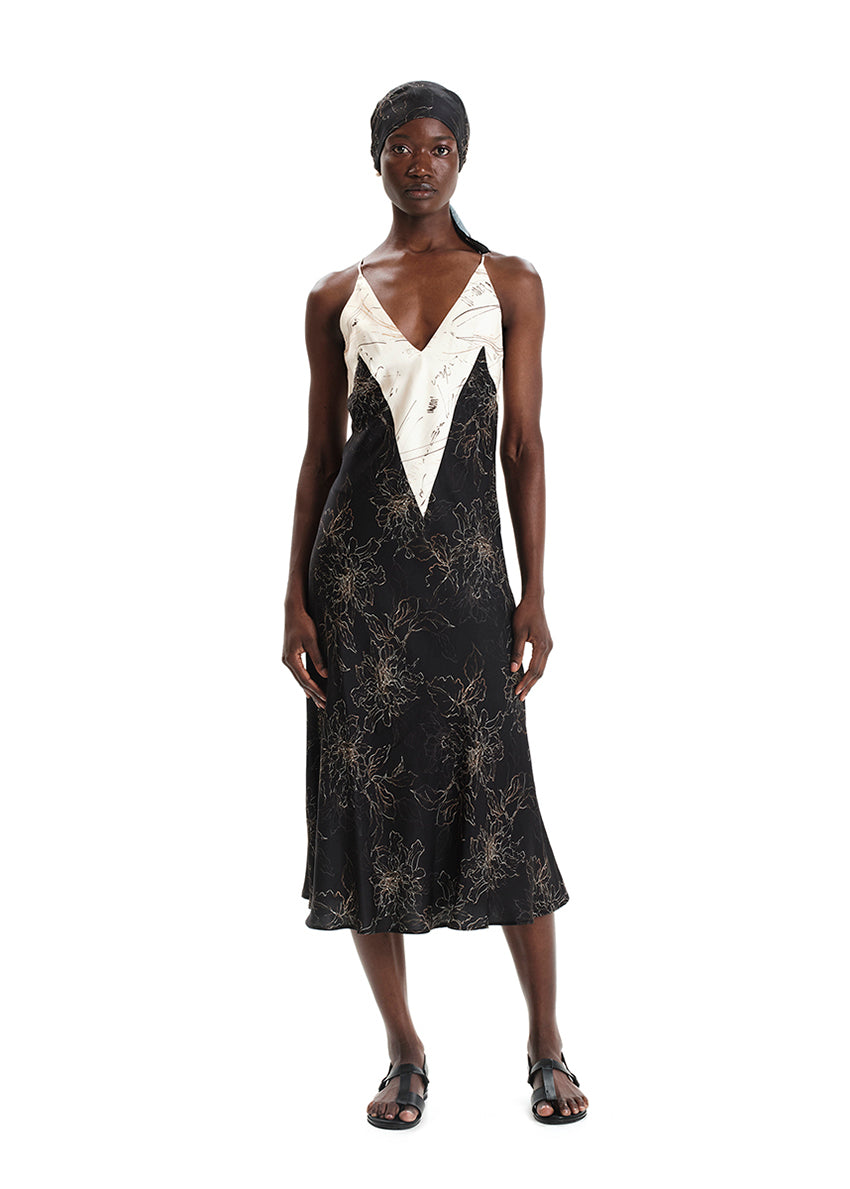 A model wearing a midi-length sleeveless dress with a floral print, a V-neckline, and tie details on the back.