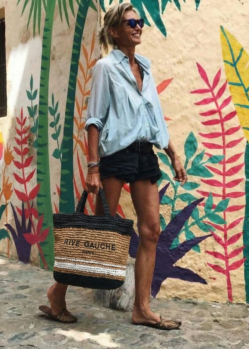 Woman holding a straw bag with a colorful mural in the background