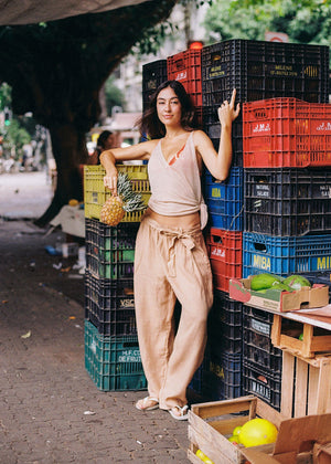 Woman standing among stacked fruit crates with a casual pose