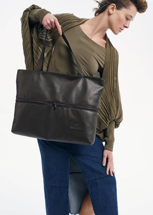 Person wearing a green blouse holding a black tote bag