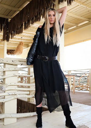 Woman in black outfit standing under a thatched roof structure
