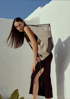 Woman in a stylish outfit against a white wall with blue sky