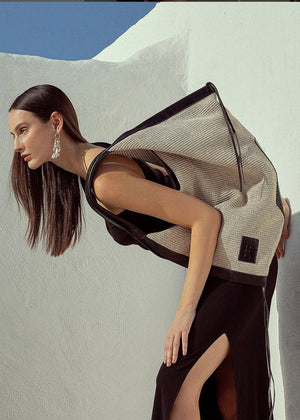 Woman wearing a modern outfit with a textured vest against a minimalistic background