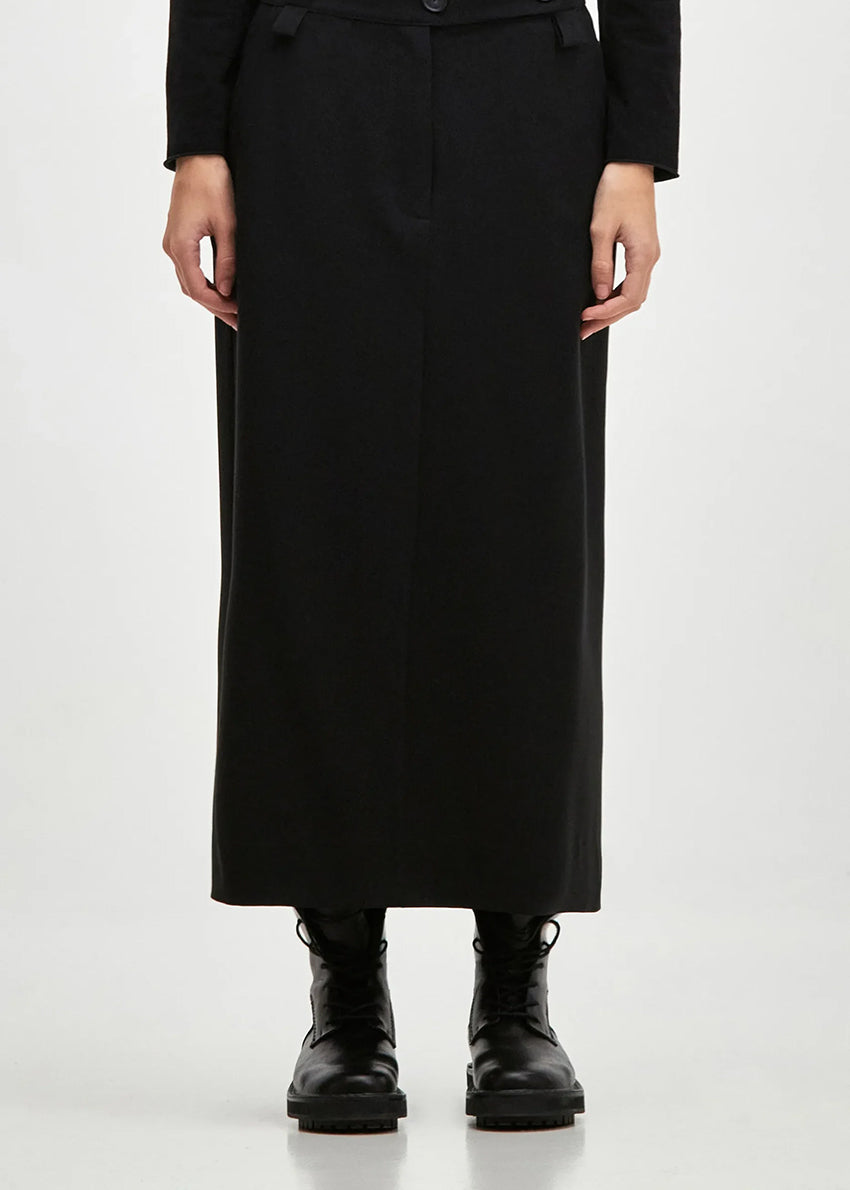 Long straight line skirt with side pockets and a slit at the back, made of blended cool wool-type viscose fabric. TUBO features a fixed waistband with elastic at the back, belt loops and closes with two front buttons and a zipper.
