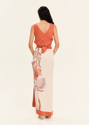 Woman wearing a rust-colored top and white skirt with floral patterns on a white background