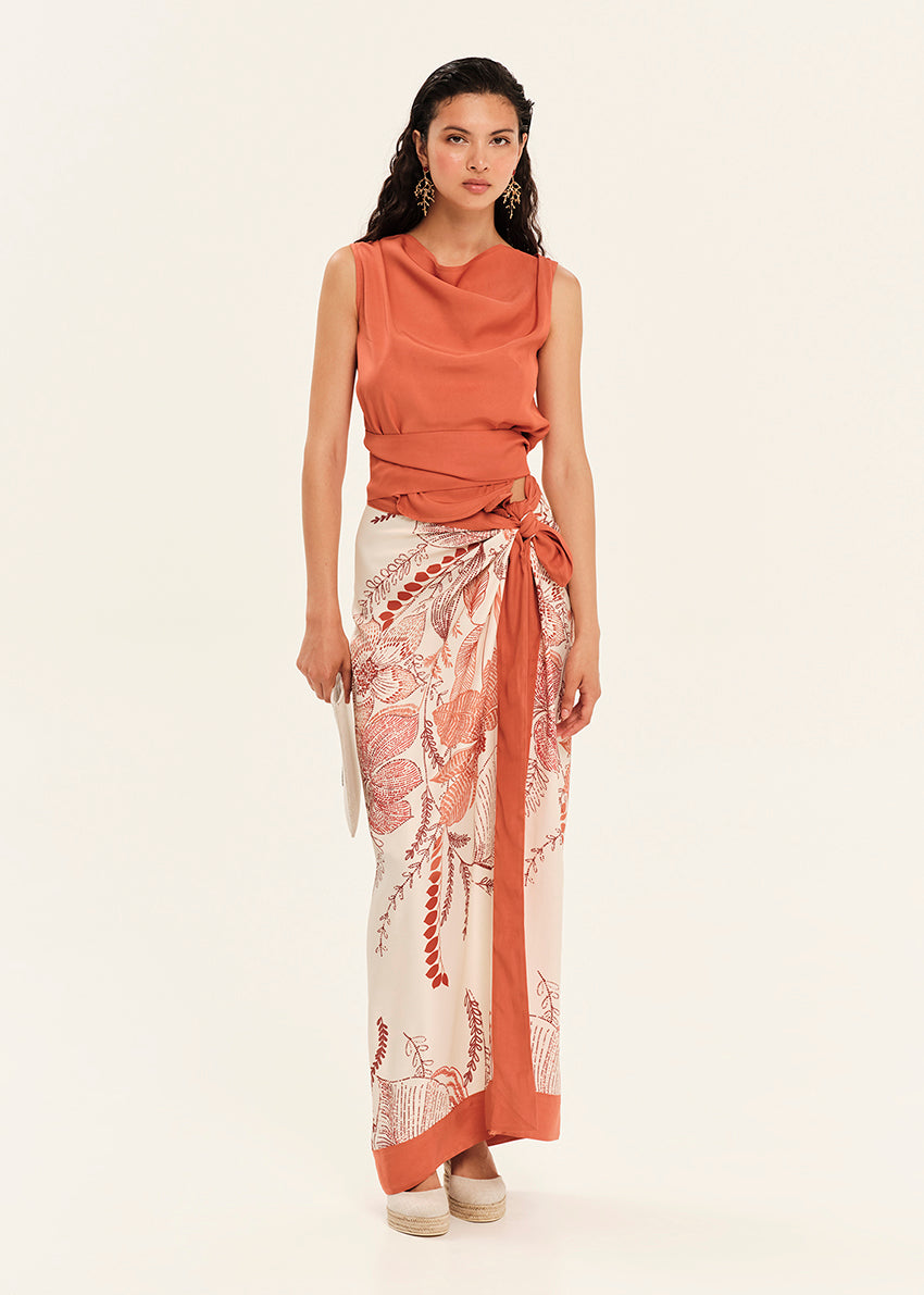 Woman wearing a rust-colored sleeveless top and a patterned skirt on a white background