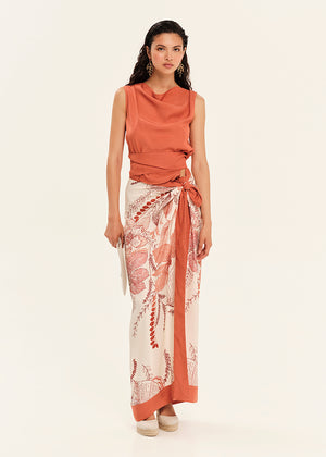 Woman wearing a rust-colored sleeveless top and a patterned skirt on a white background