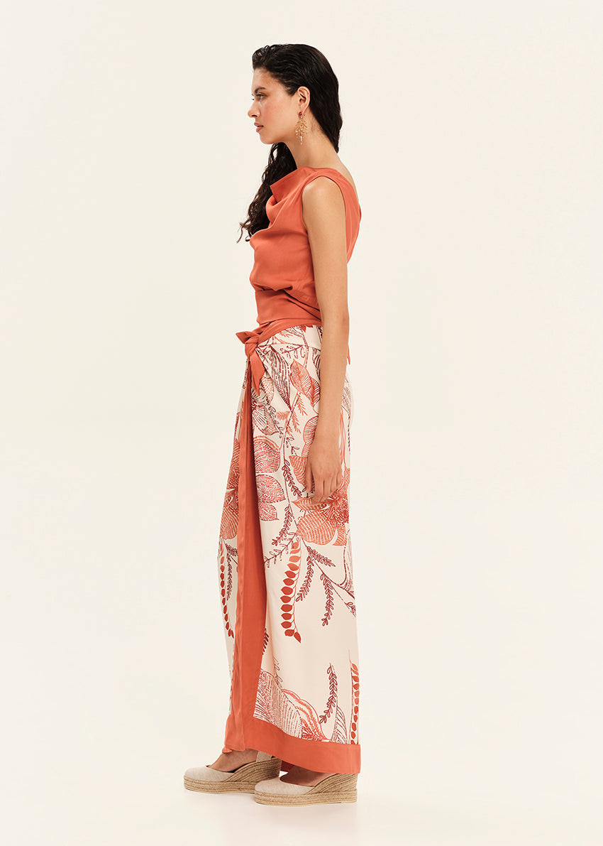 Woman wearing a rust-colored sleeveless top and floral skirt on a white background