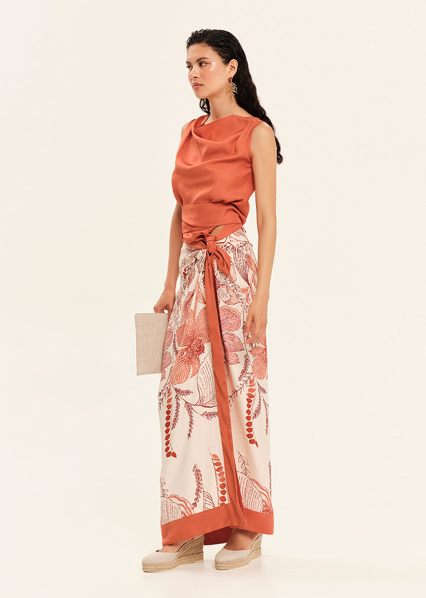 Woman wearing a rust-colored top and floral skirt on a white background
