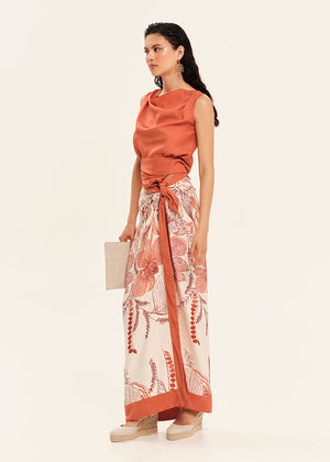 Woman wearing a rust-colored top and floral skirt on a white background