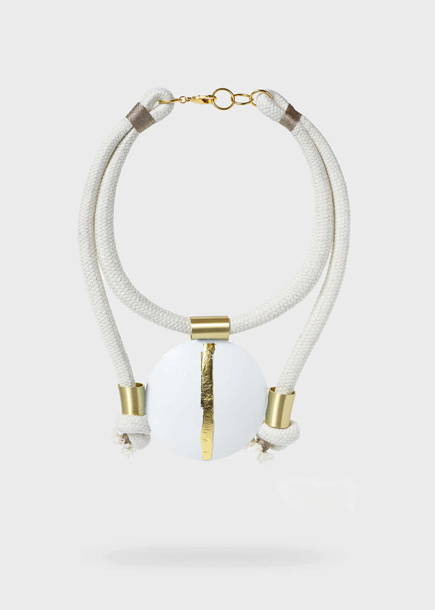 Necklace with white beads and gold accents on a light gray background