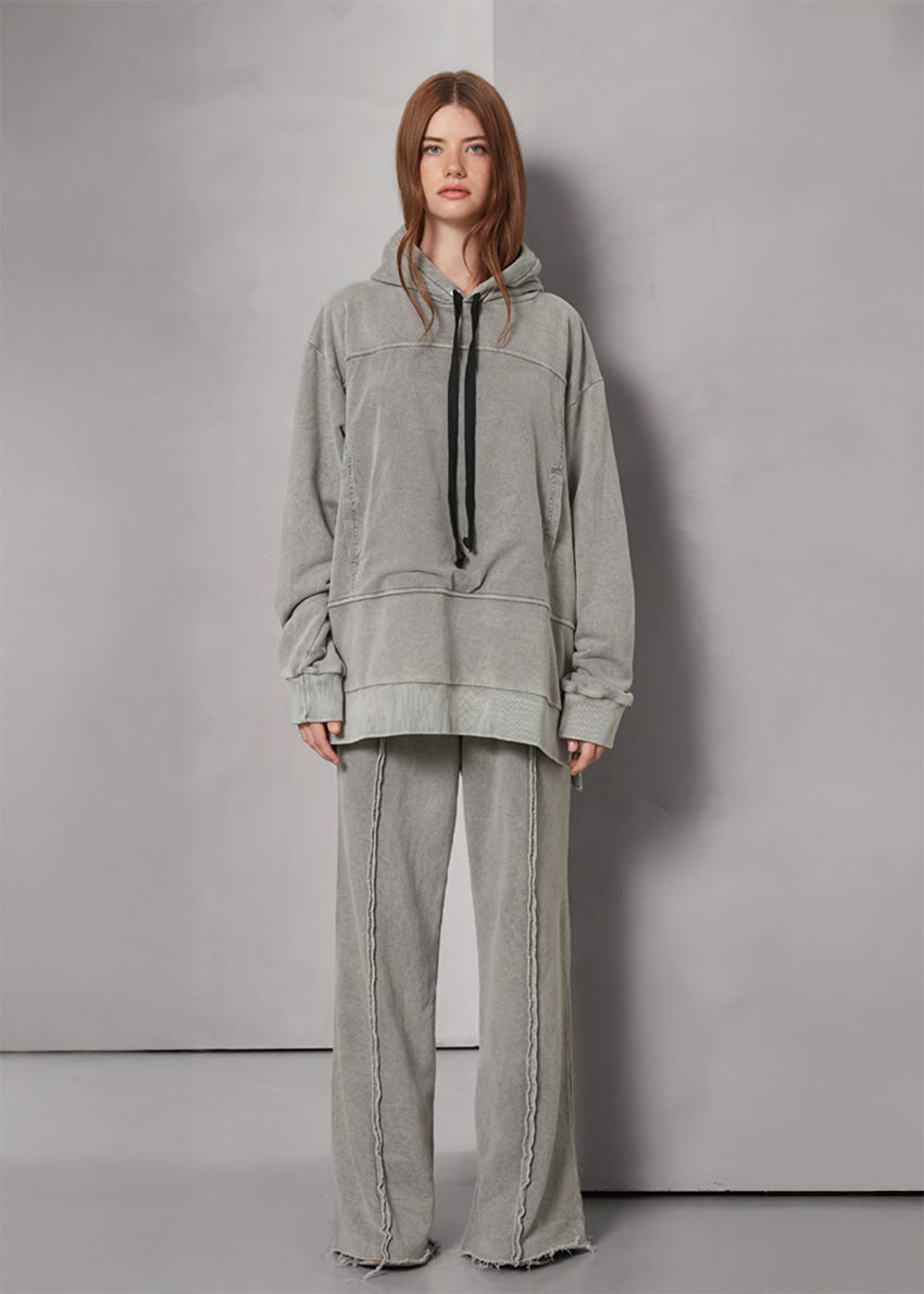 Person wearing a gray hoodie and pants against a plain background