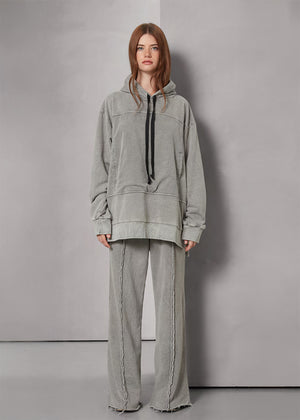 Person wearing a gray hoodie and pants against a plain background