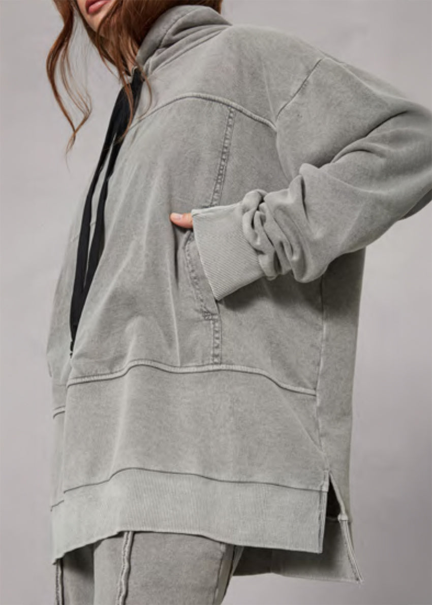 Person wearing a gray oversized jacket on a plain background
