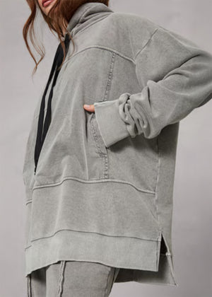 Person wearing a gray oversized jacket on a plain background