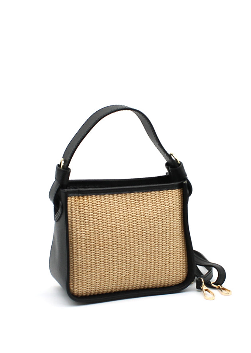 A black handbag with a natural woven panel and leather accents, featuring an adjustable strap and sturdy handle.