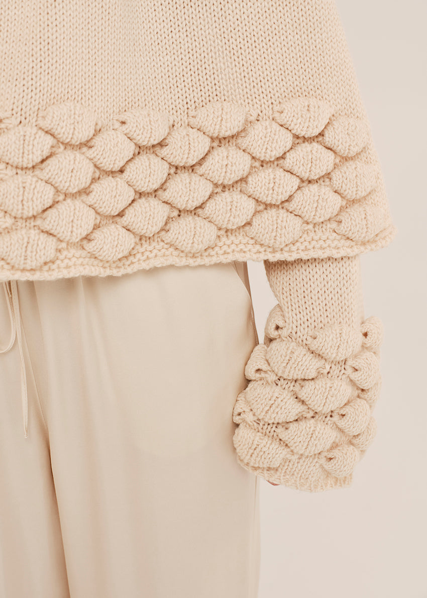 Beige knit scarf with textured pattern against a neutral background