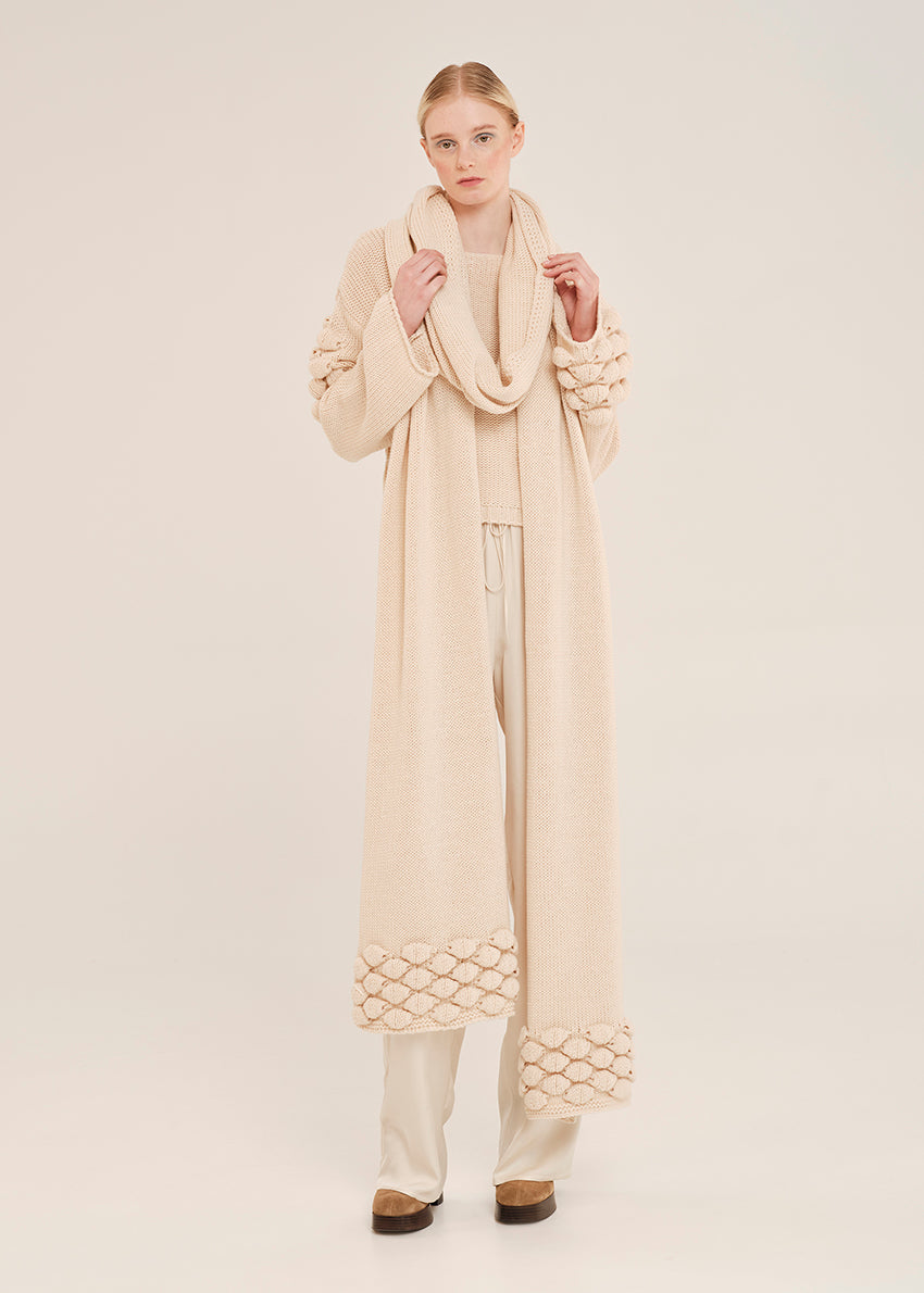 Woman wearing a long scarf with textured details on a white background