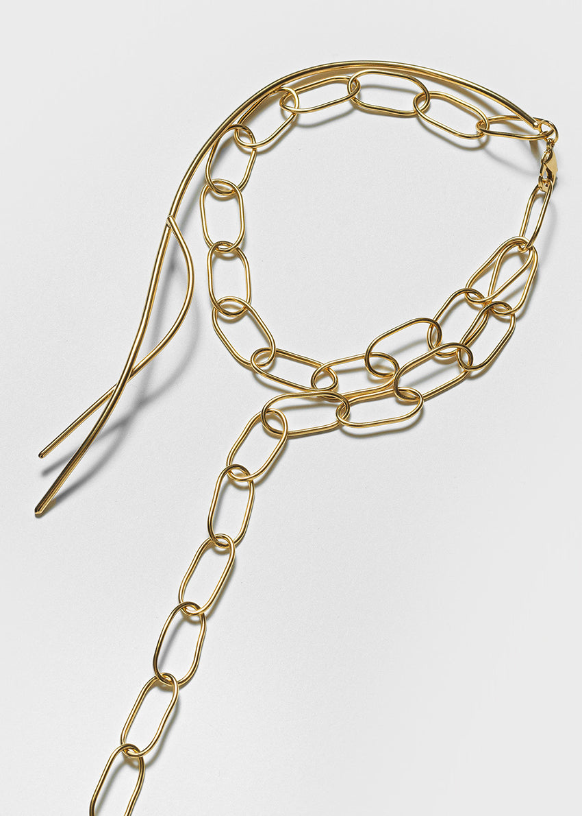 Gold chain necklace on a light gray background