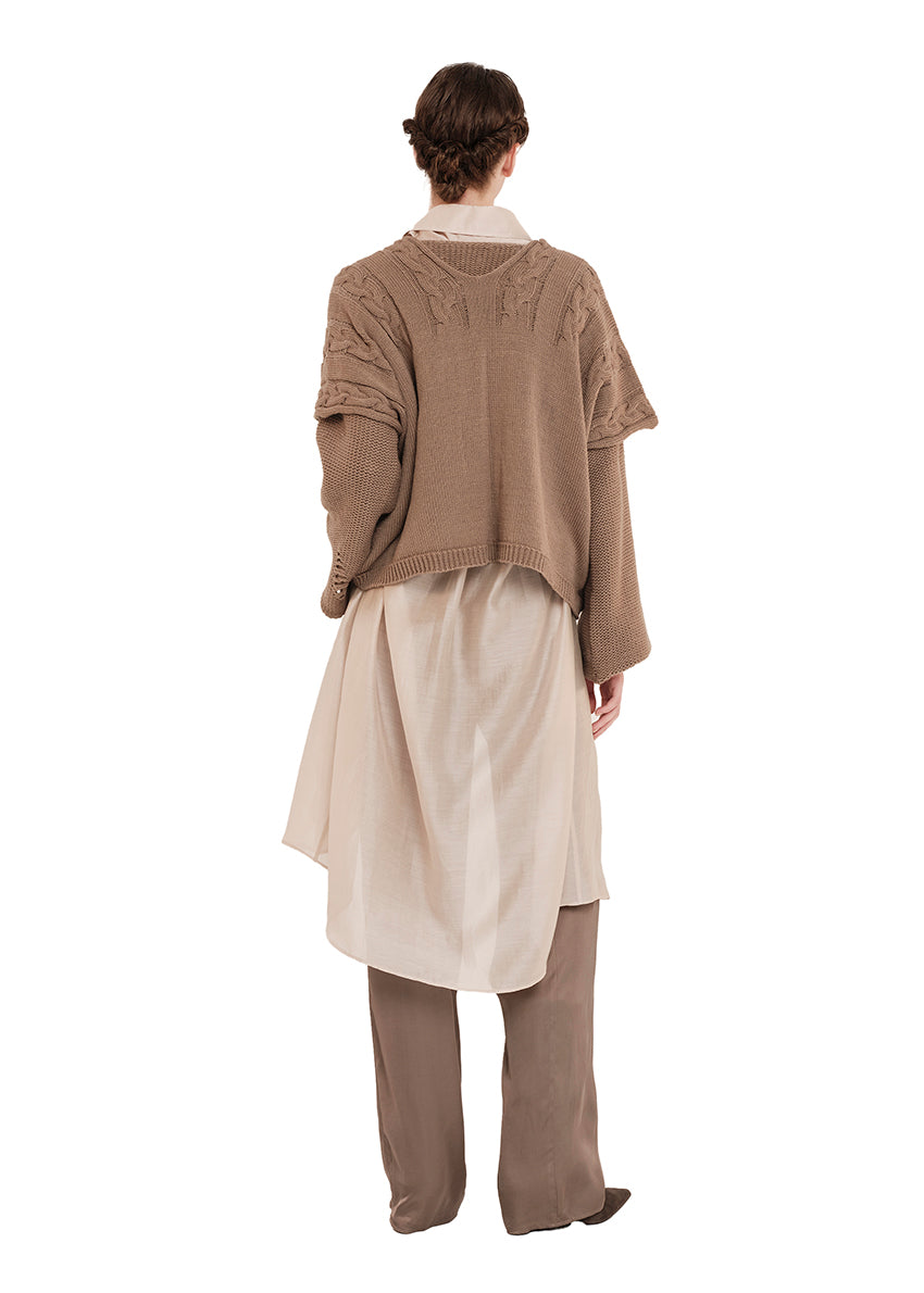 Person wearing a beige vest, white shirt, and beige pants on a white background