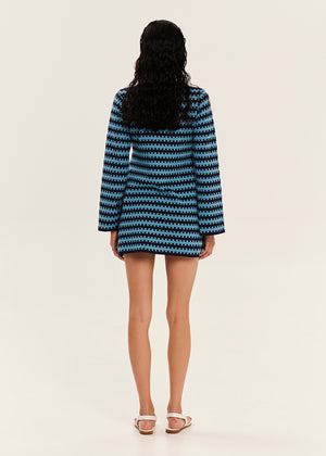 Person wearing a blue and black patterned coat on a white background