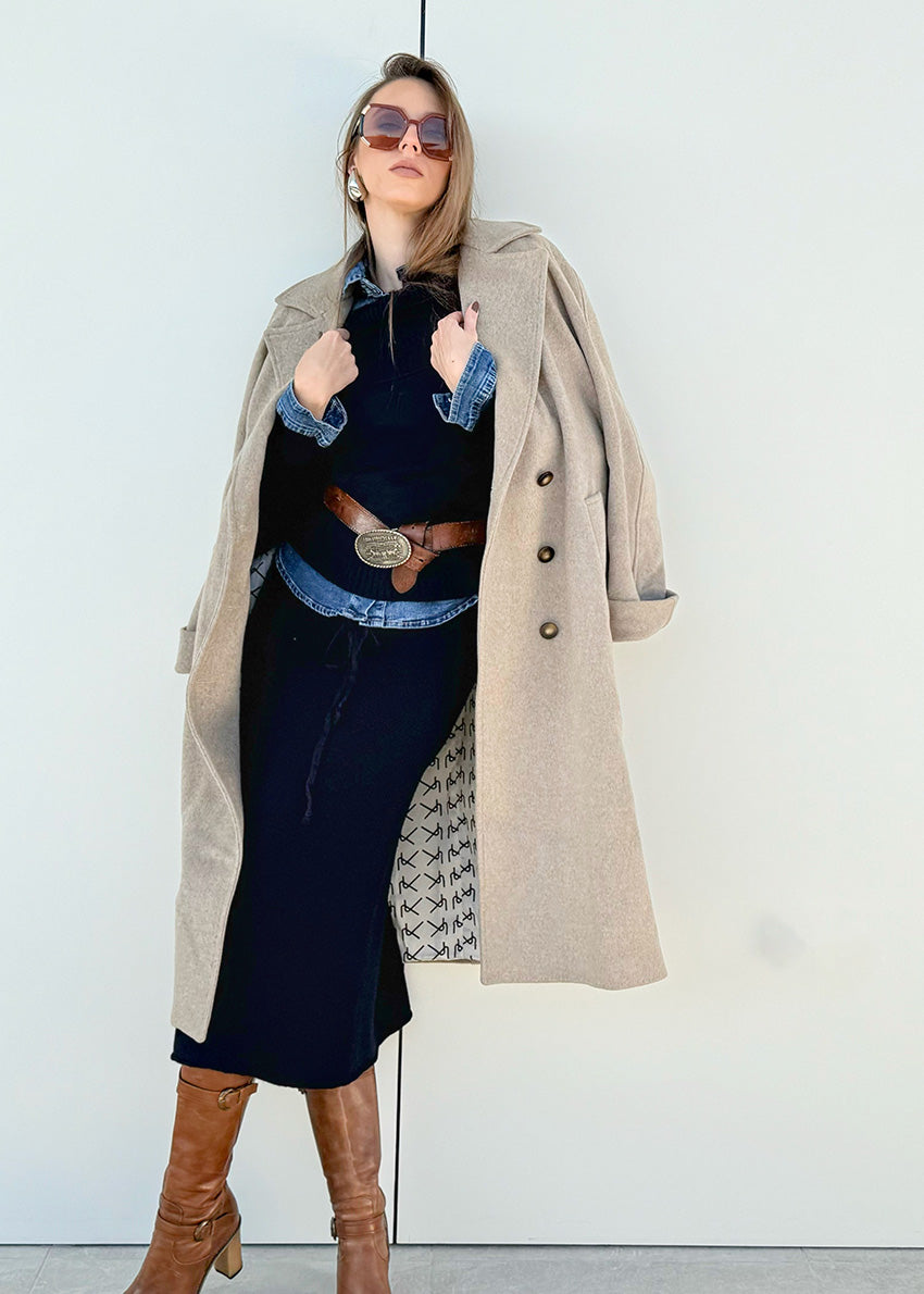 Person wearing a beige wool coat with a black dress and brown boots