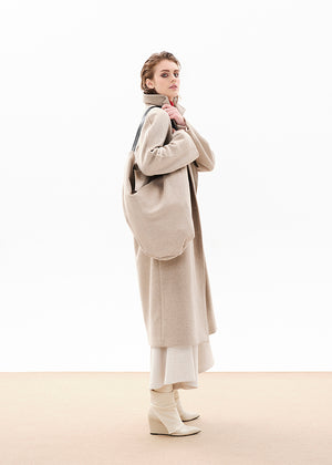 Person wearing a beige wool coat with a matching bag 