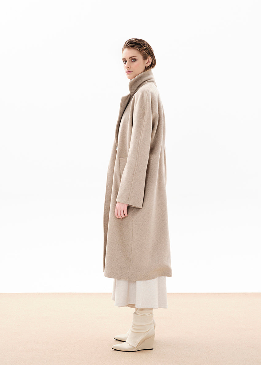 Person wearing a beige wool coat from the side on a white background 