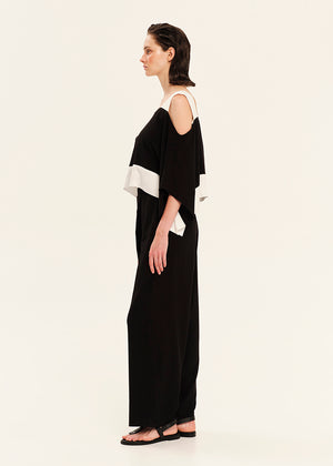 Woman wearing a black and white top with black pants on a white background