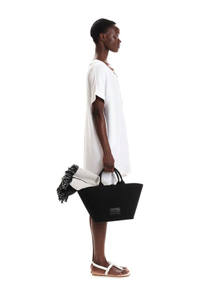 White tunic with front detail made of a linen and bamboo blend with a linen look.It has a boxy shape with short sleeves and mini length. It has a plunging “V” neck with ribbons that tie in “X” shapes while the fringes at the seams highlight its raw look.