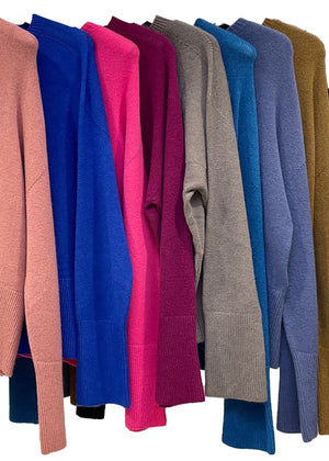 Row of colorful sweaters on a white background