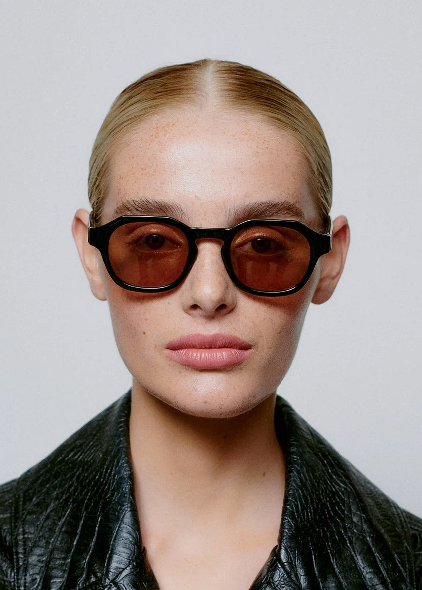 Round sunglasses with black frame and brown lenses on a white background
