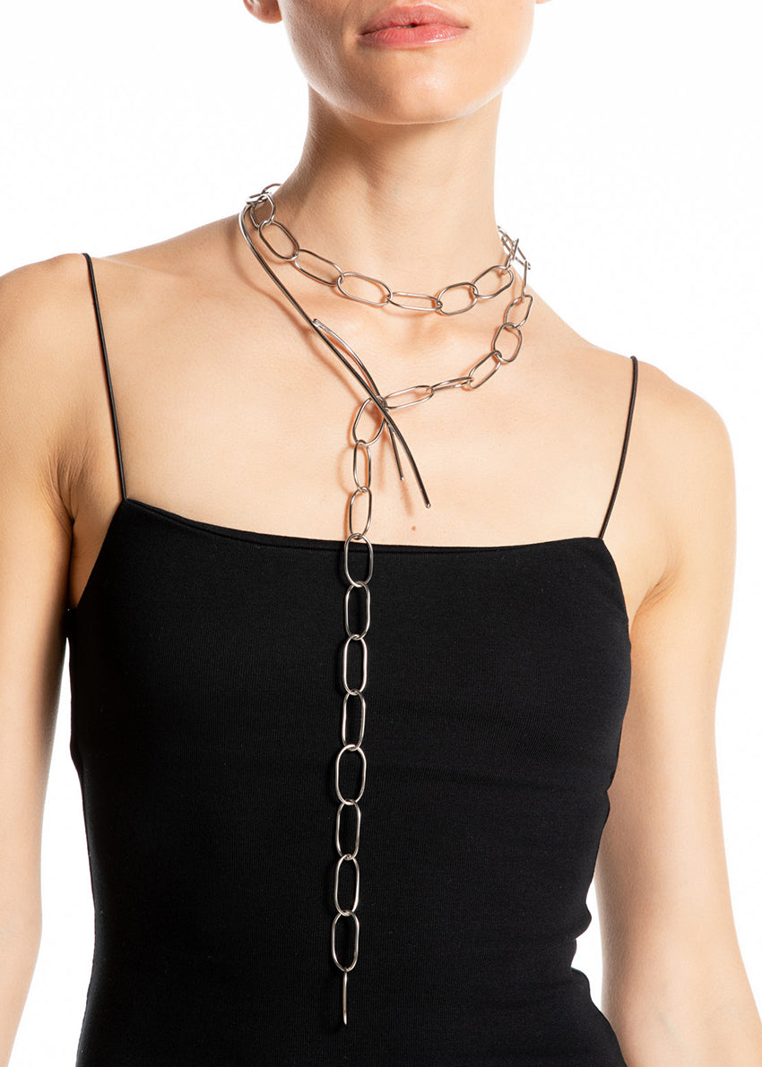 Woman wearing a black dress with a long chain necklace on a white background