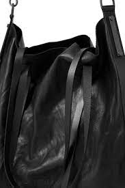 Black leather handbag with a strap on a black background
