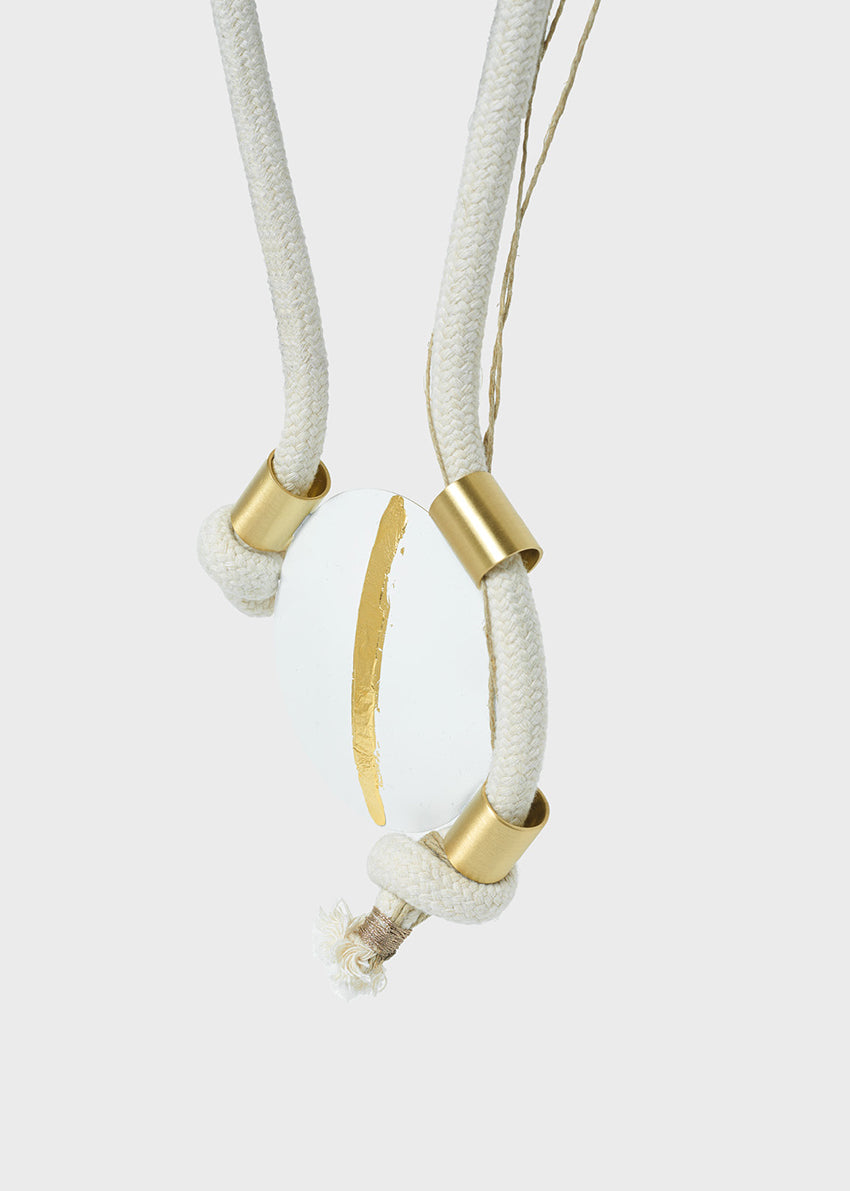 Necklace with gold and white elements on a light gray background