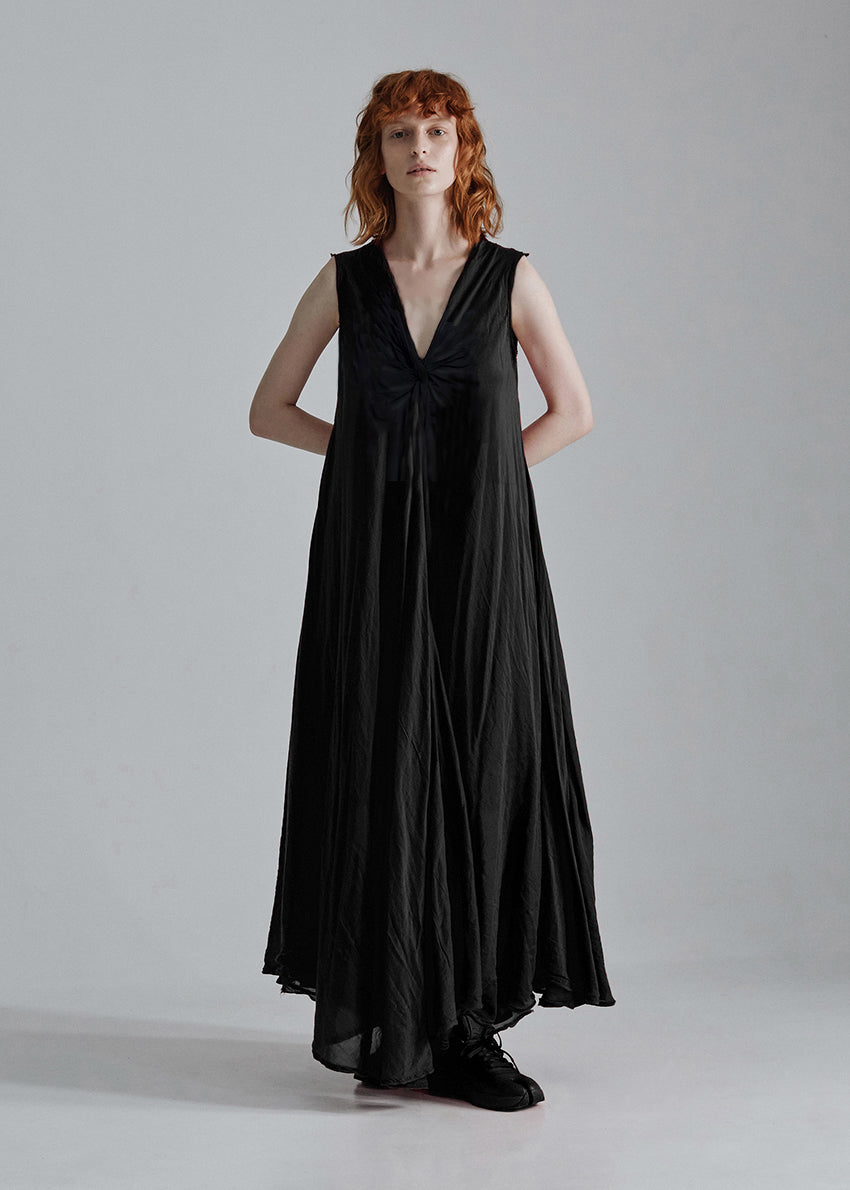 Woman wearing a black sleeveless dress against a plain background