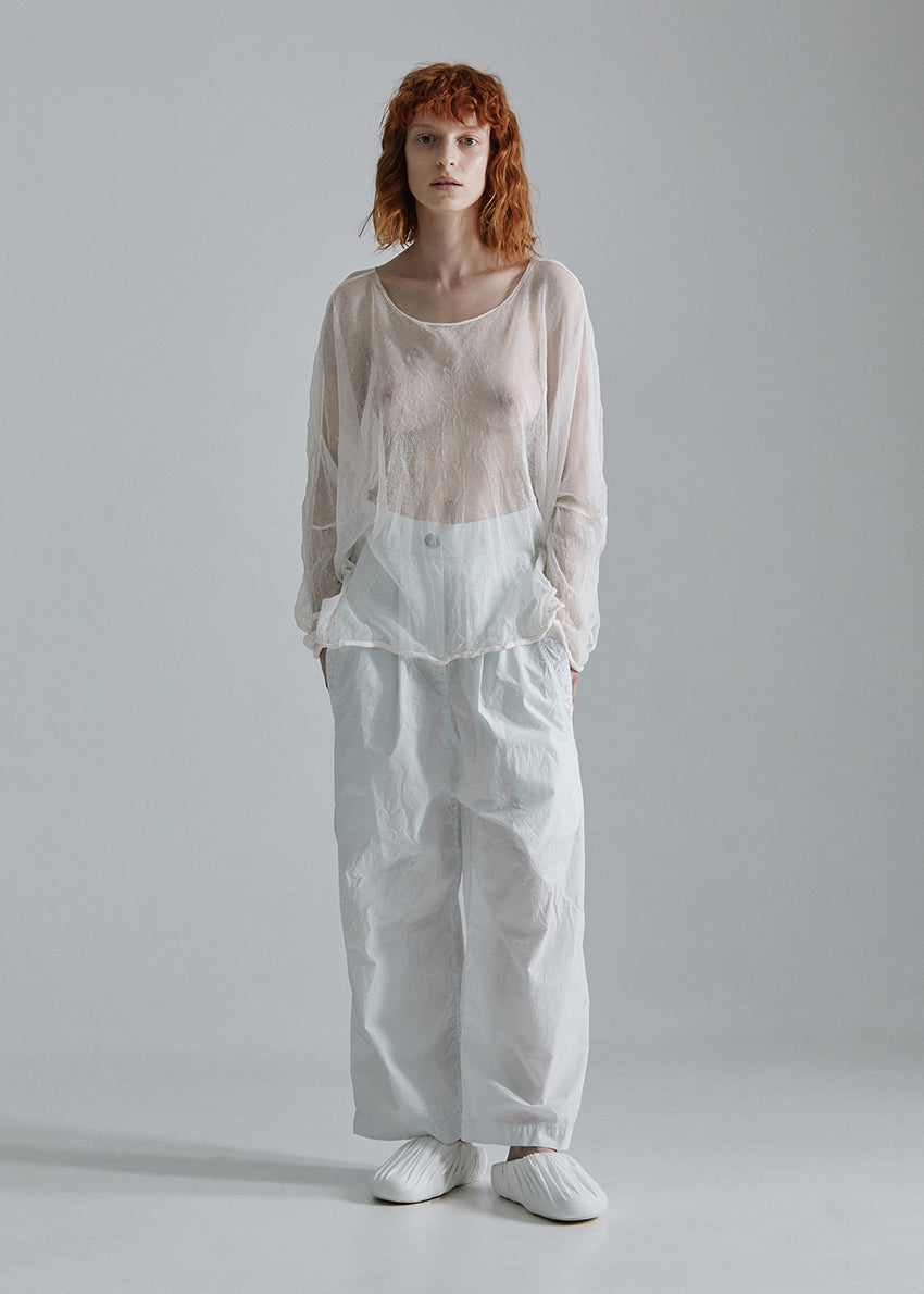 Person wearing a white top and light blue pants on a gray background