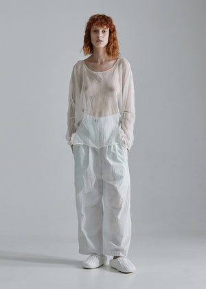 Person wearing a white top and light blue pants on a gray background