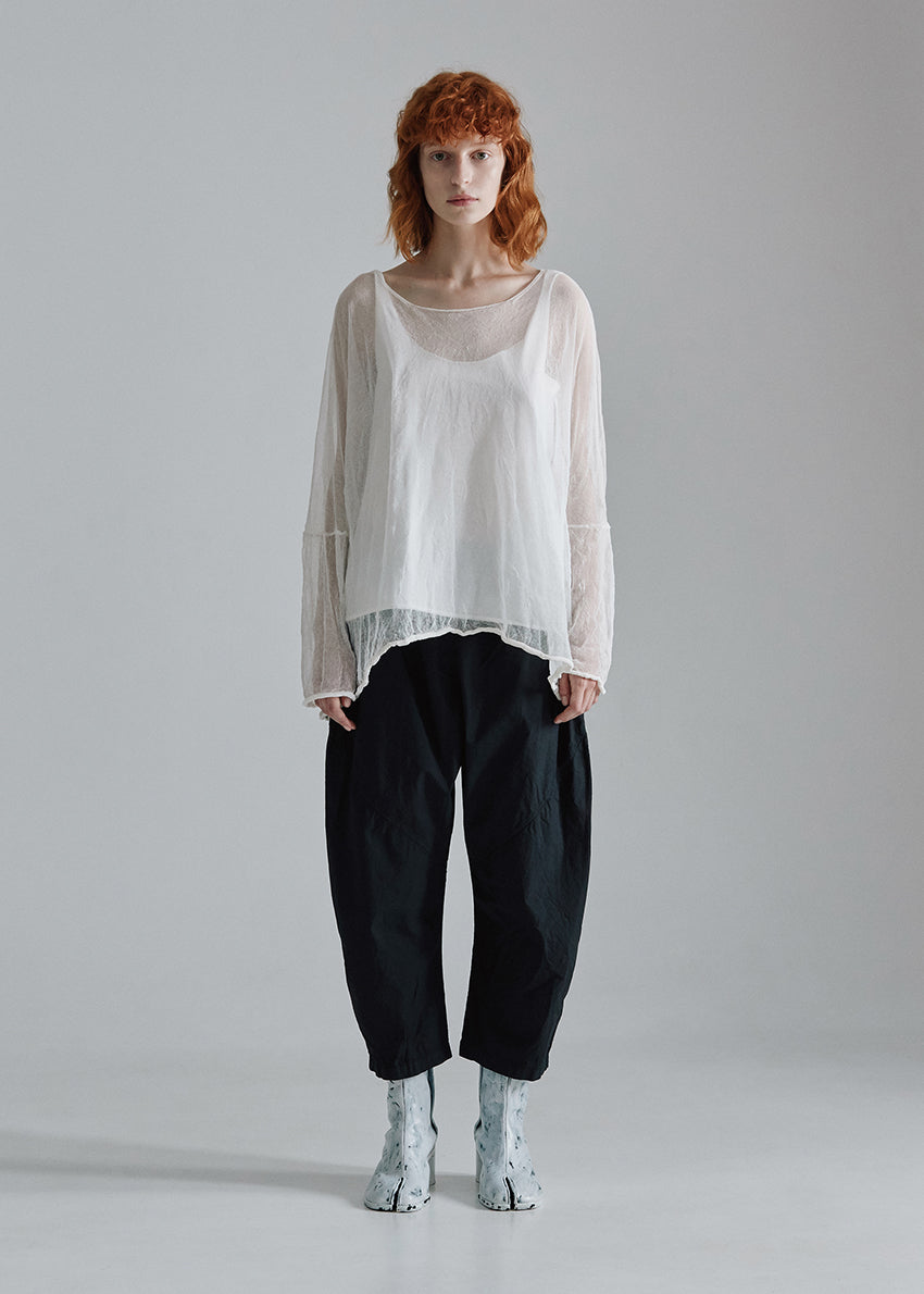 Person wearing a white blouse and black pants on a gray background