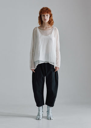 Person wearing a white blouse and black pants on a gray background