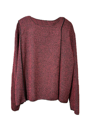 A red unisex top with a crepe texture, featuring a relaxed fit with slightly dropped shoulders and diagonal seams along the upper sleeves.