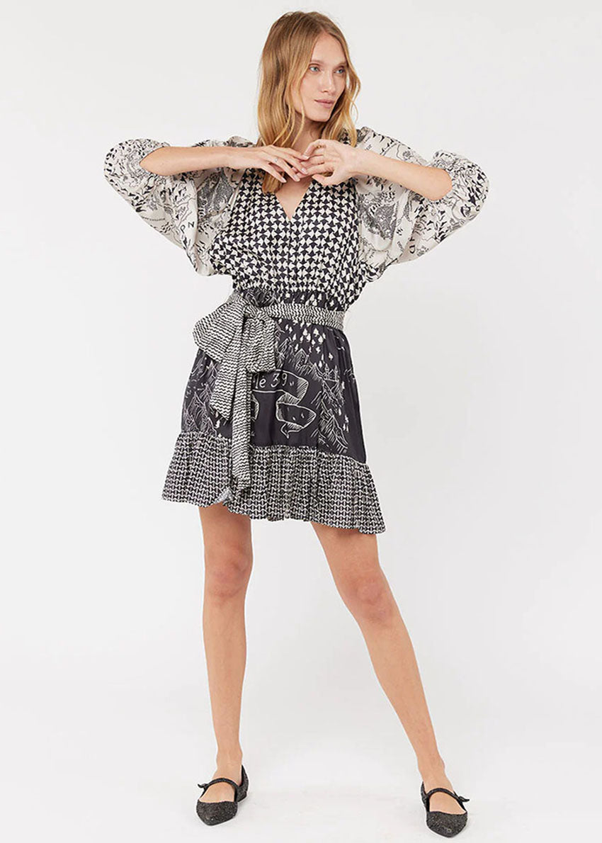 A woman modeling a black and white geometric patterned dress with bell sleeves and a belt.