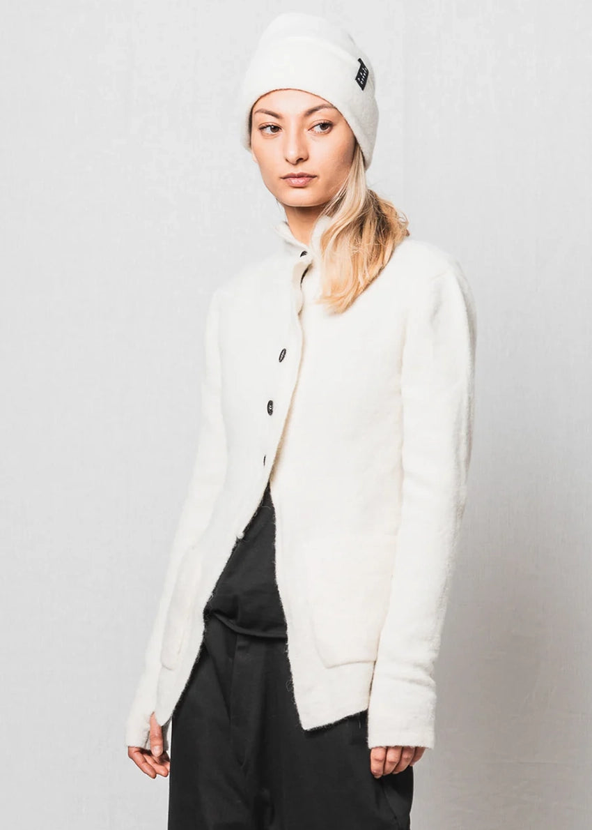 Person wearing a white jacket and beanie on a plain background