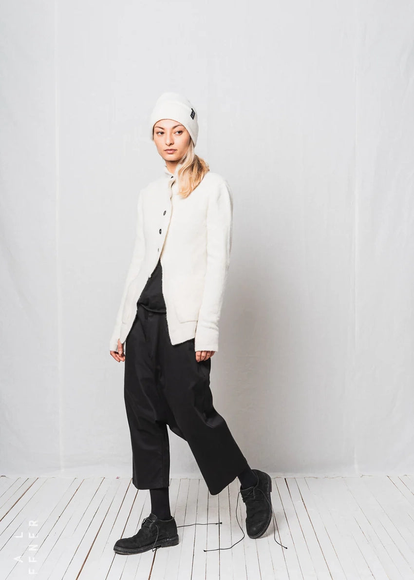 Person wearing a white beanie, white jacket, black pants, and black shoes on a white background
