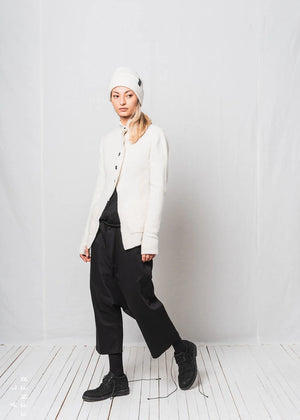 Person wearing a white beanie, white jacket, black pants, and black shoes on a white background