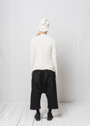Person wearing a white jacket and black pants against a plain white background